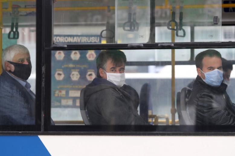 People wearing protective masks look on in a bus in Ankara