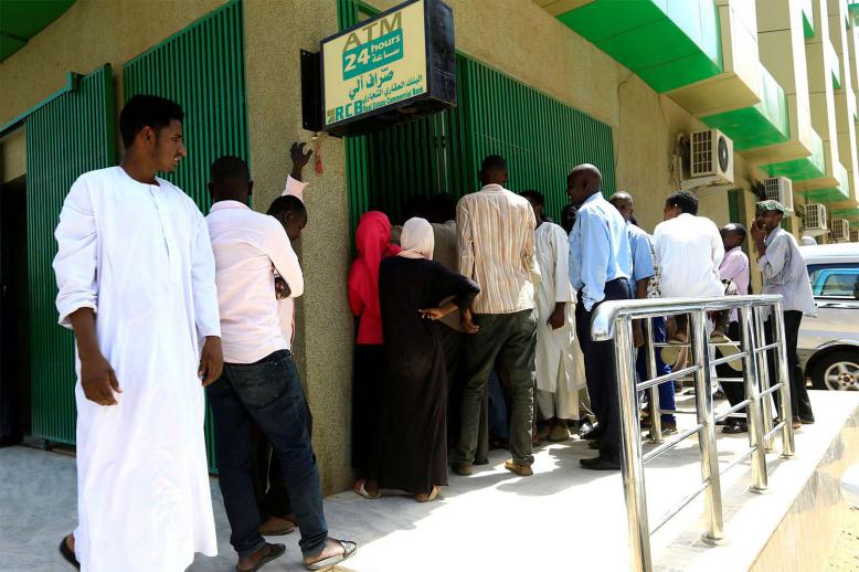 People queue to withdraw money from an automated teller machine, ATM, in Khartoum