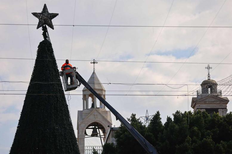 A worker sets up lights on a giant Christmas tree at the Church of the Nativity compound 