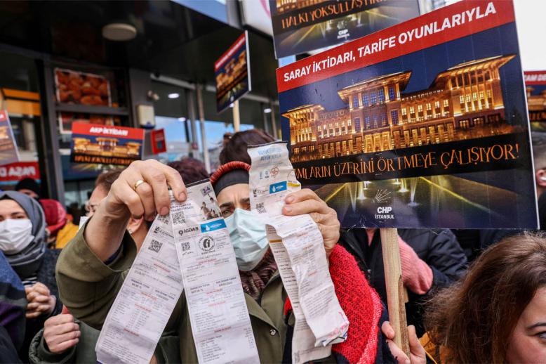 A woman displays her utility bills during a protest against high energy prices in Istanbul