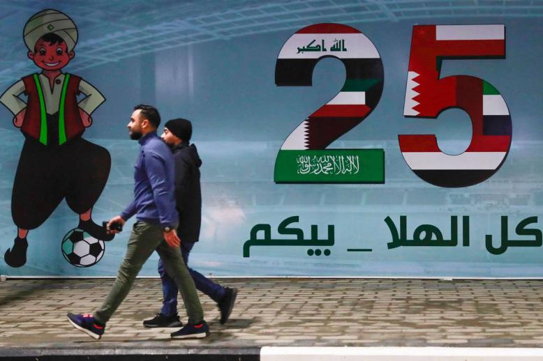 عراقيون يمرون بجانب جدارية تحتفي بخليجي 25