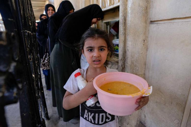 طفلة عراقية تحمل شورية يوزعها مسجد عبدالقادر الكيلاني وسط بغداد