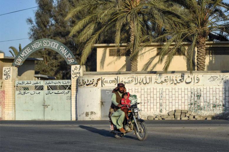 A motorcyclist rides past a high school at Panjgur district in Balochistan province 