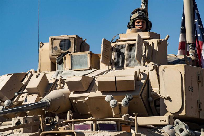 A US soldier monitors the area as troops patrol oil fields near Syria's northeastern border with Turkey