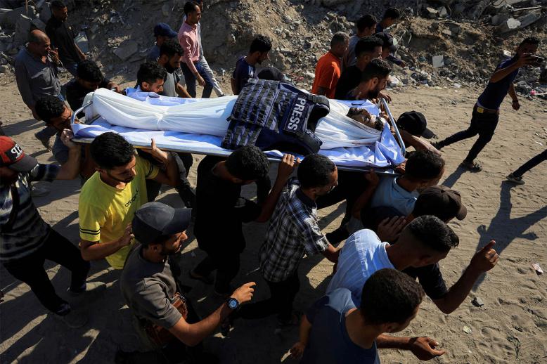 People carry the body of a Palestinian journalist, Adam Abu Harbid, killed in an overnight Israeli airstrike