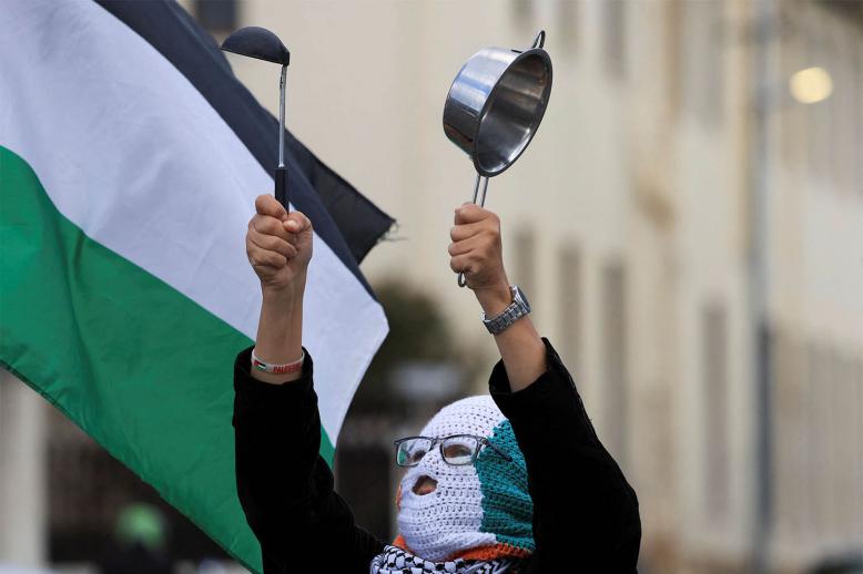 A pro-Palestinian activist makes noise with a pot in a protest over the hunger crisis in Gaza, outside the parliament in Cape Town