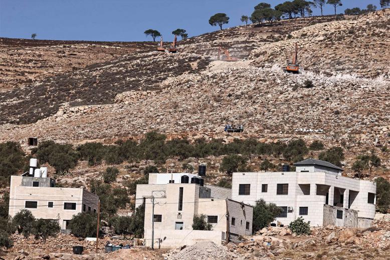 Israeli settlers use bulldozers to pave a road for a new settlement on the outskirts of the occupied West Bank village of Al-Mughayyir, north of Ramallah