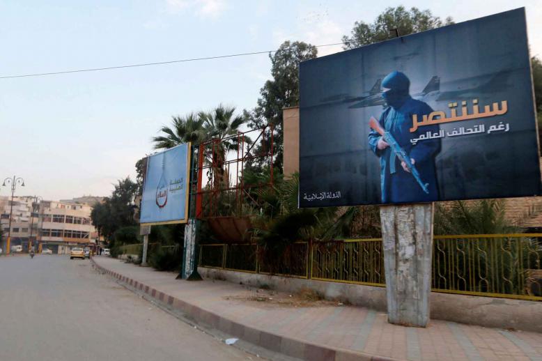 A 2014 file picture shows Islamic State billboards are seen along a street in Raqqa, eastern Syria. The billboard (R) reads: “We will win despite the global coalition.” 