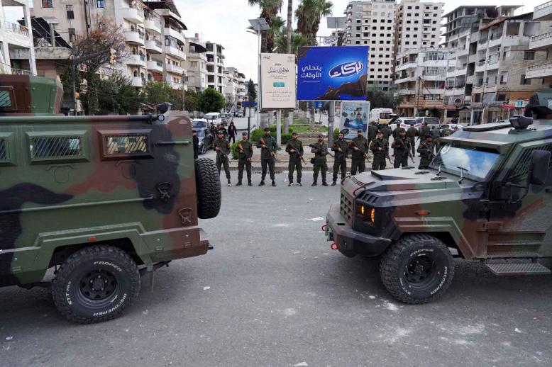 Members of the Syrian Security forces stand guard near military vehicles on the day people from the Alawite sect protest as they demand federalism, in Latakia, Syria, December 28, 2025. 