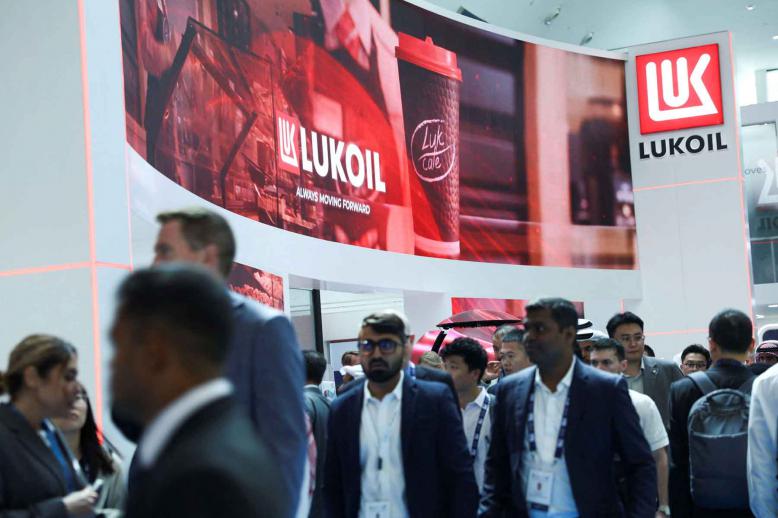 People walk past the booth of Lukoil during the annual energy industry event Abu Dhabi International Petroleum Exhibition and Conference (ADIPEC) in Abu Dhabi, November 3, 2025. 