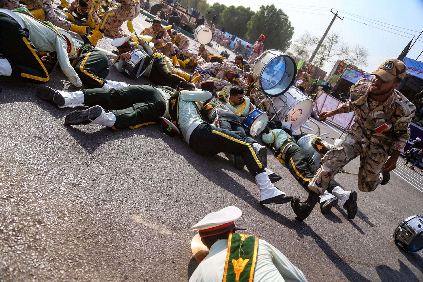 A soldier running past injured comrades lying on the ground at the scene of an attack in Ahvaz