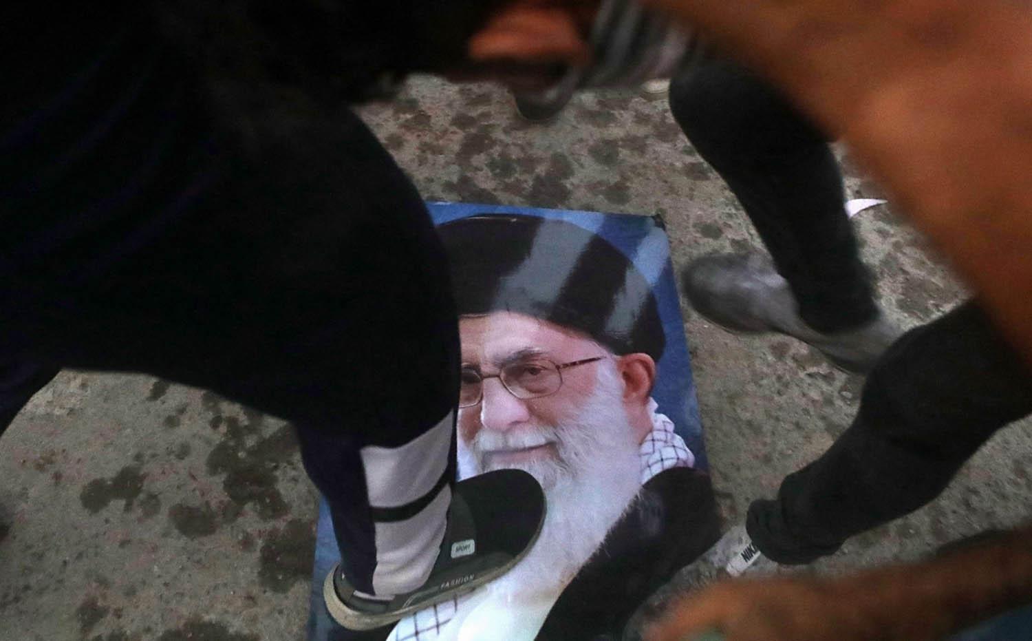 متظاهرون عراقيون يدوسون صورة المرشد الأعلى خامنئي بعد اقتحامهم للقنصلية الإيرانية في البصرة