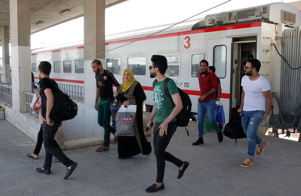 مسافرون ينزلون من القطار بعد وصولهم محطة الفلوجة قادمين من بغداد