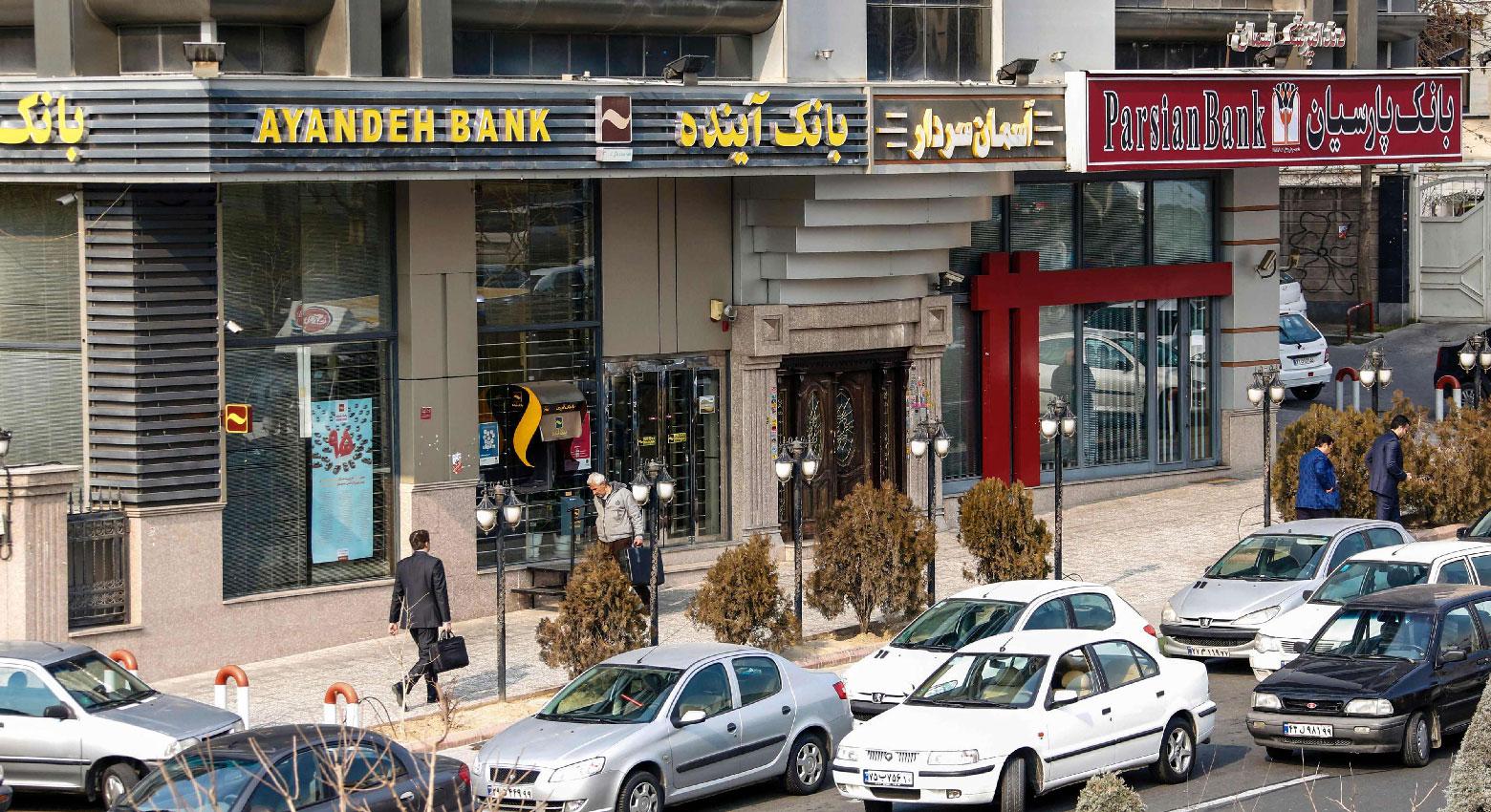 Iranians walk past a Bank Ayandeh and Parian, on the first anniversary of the nuclear agreement, in the capital Tehran on Jaunary 14, 2017.