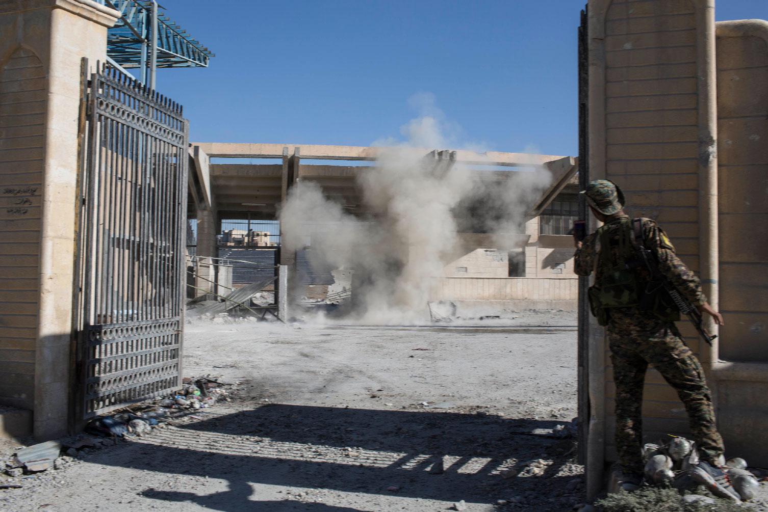 A member of the U.S.-backed Syrian Democratic Forces SDF throws a bomb to check for more explosives as they clear the stadium that was the site of Islamic State fighters' last stand in the city of Raqqa, Syria.