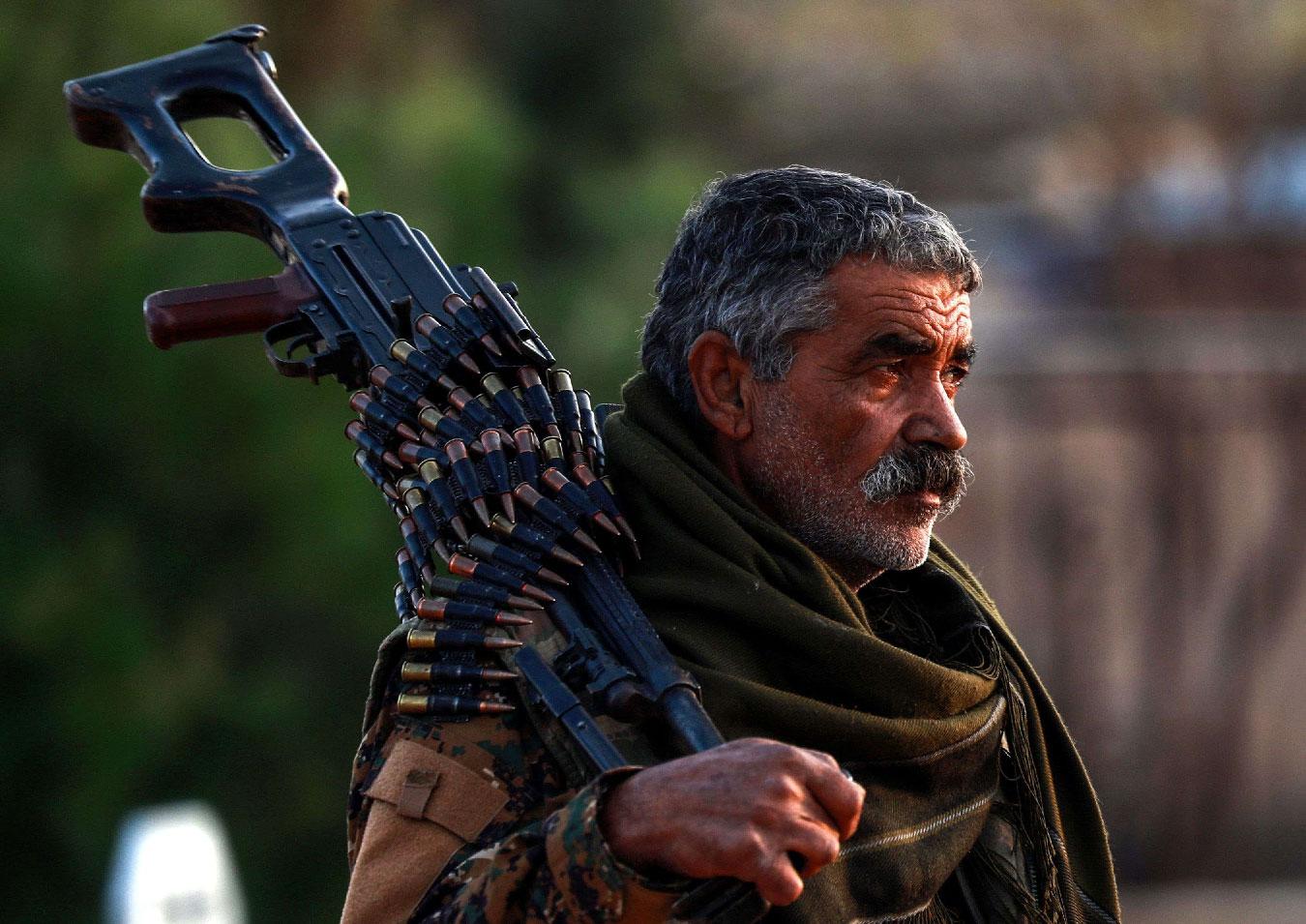 A Syrian Democratic Forces (SDF) fighter holds a machine gun on his shoulder as he attends the funeral of a slain People's Protection Units (YPG) commander in the northeastern city of Qamishli on December 6, 2018.