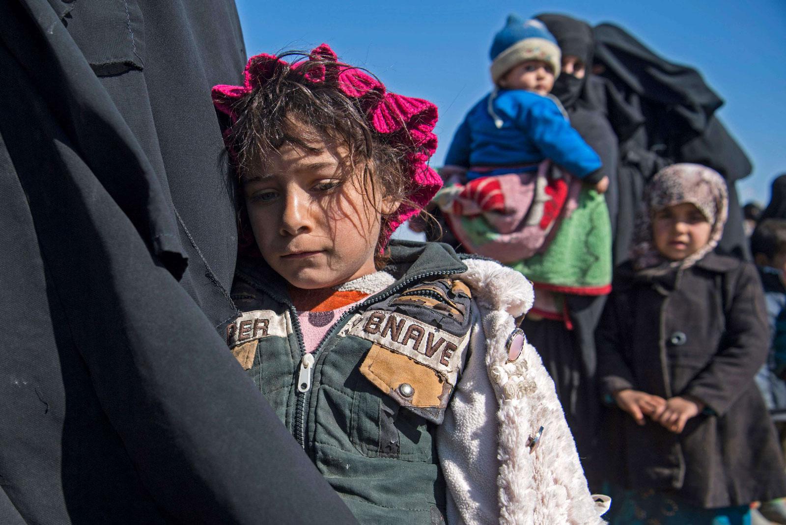 Women and children stand in a field after they fled from the Baghouz area in the eastern Syrian province of Deir Ezzor on February 12, 2019 during an operation by the US-backed Syrian Democratic Forces (SDF) to expel hundreds of Islamic State group (IS) jihadists from the region.