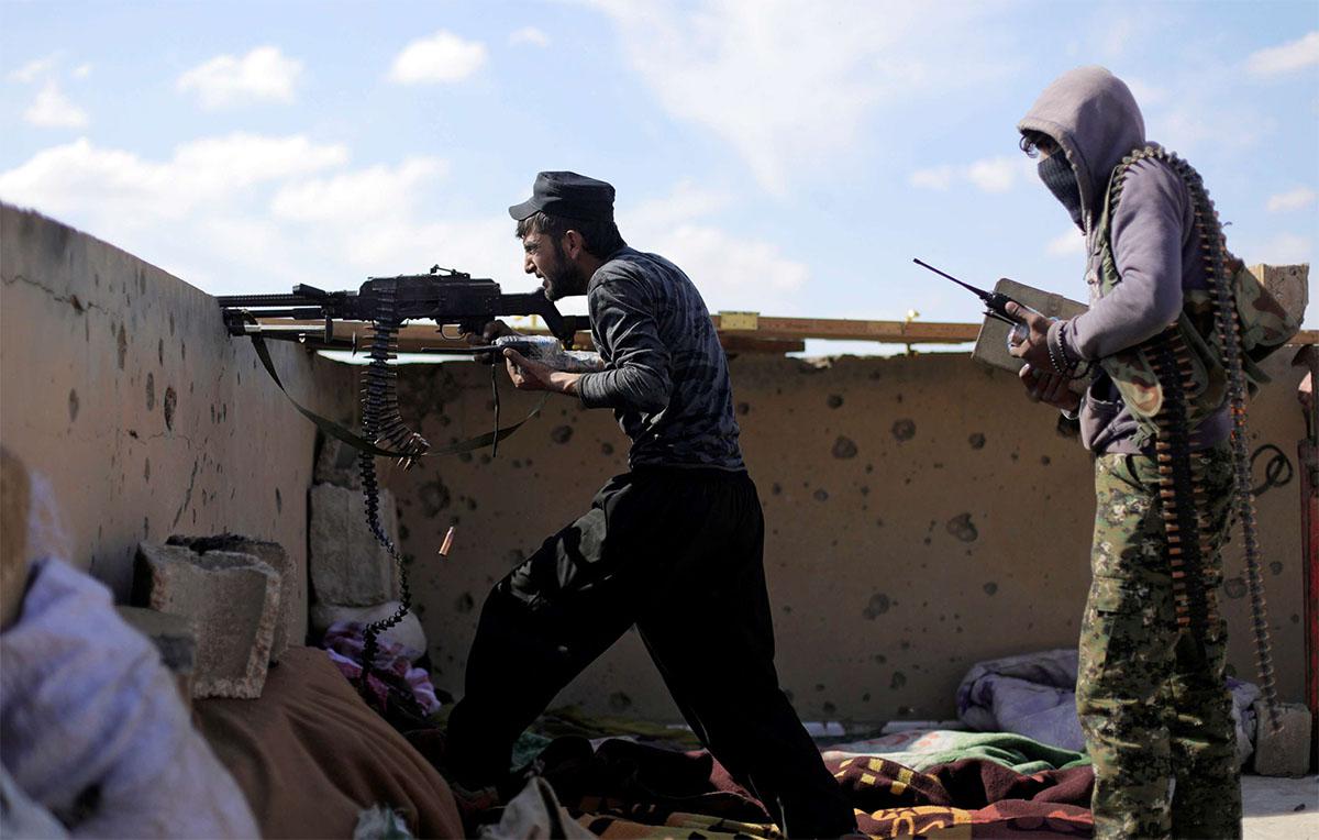 A fighter of Syrian Democratic Forces (SDF) fires a weapon in Baghouz