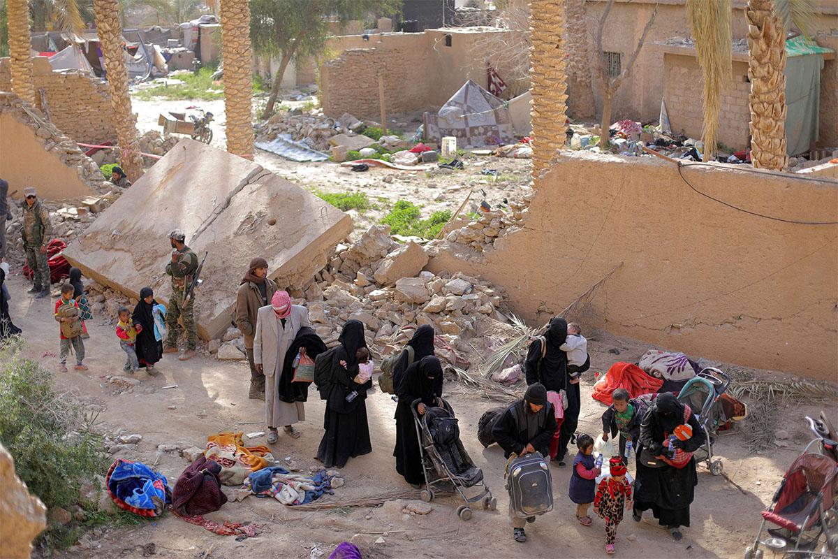 Islamic state fighters and their families walk as they surrendered in the village of Baghouz