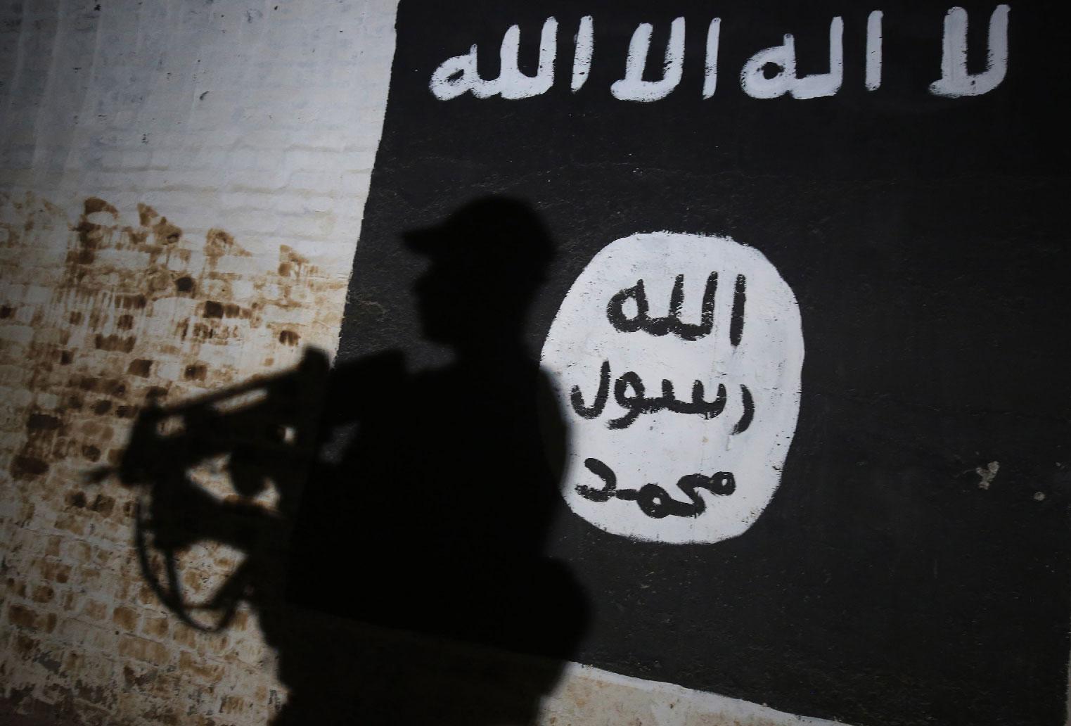 A member of the Iraqi forces walks past a mural bearing the logo of the Islamic State (IS) group in a tunnel that was reportedly used as a training centre by the jihadists in the village of Albu Sayf, on the southern outskirts of Mosul.