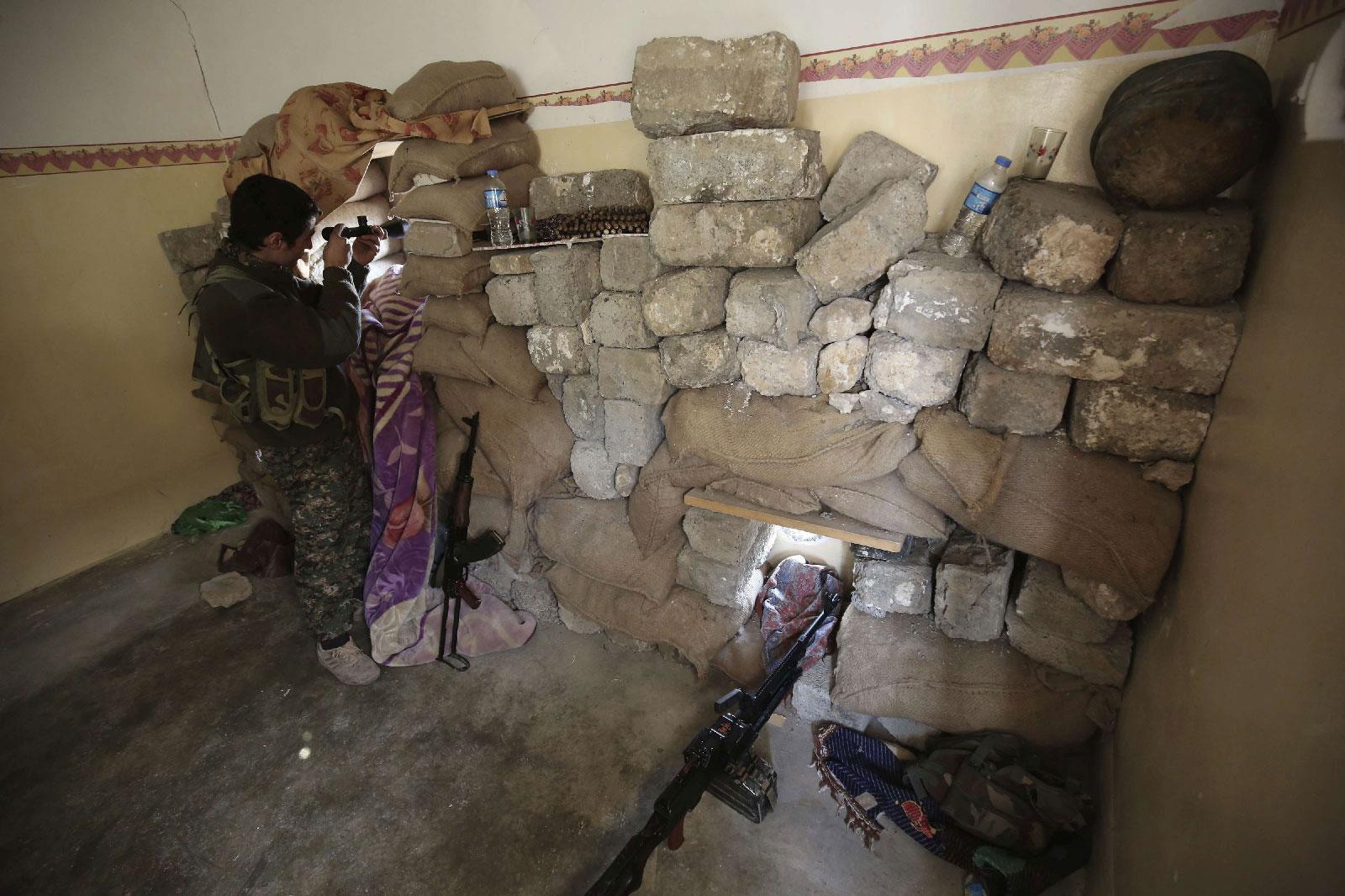 Jan. 29, 2015 photo shows a fighter of the Turkey-based Kurdish Workers' Party (PKK) uses his binoculars to look towards the Islamic State Group's base in the city of Sinjar, northern Iraq.