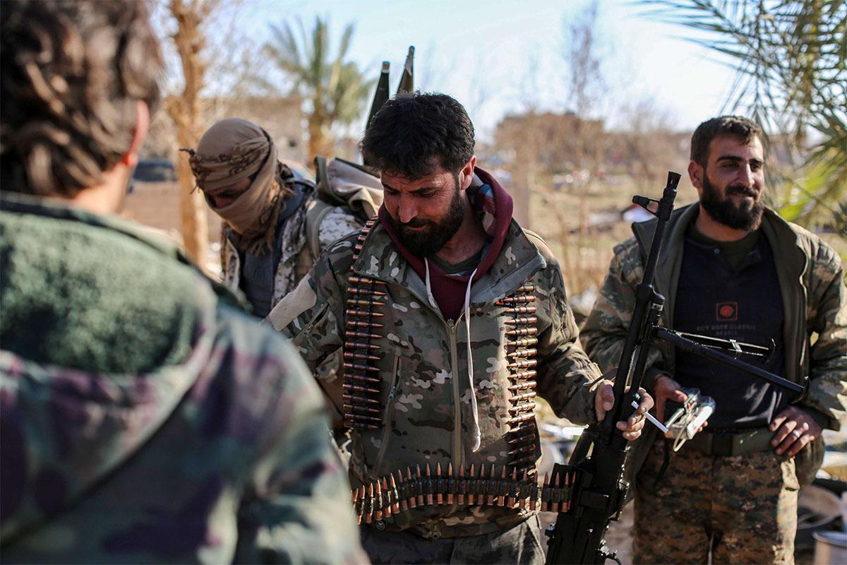 Syrian Democratic Forces (SDF) stand at a makeshift camp for IS group members and their families in Baghouz