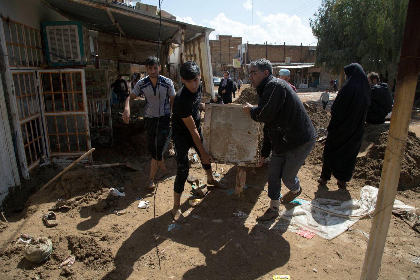 Iranians carry furnitures in a flooded street in the city of Poldokhtar in the Lorestan province, on April 02, 2019.