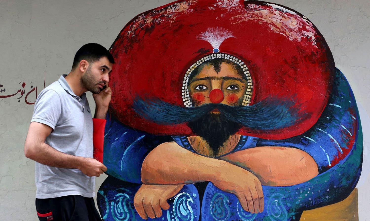 إيراني يمر بجانب تخطيط على حائط وسط طهران