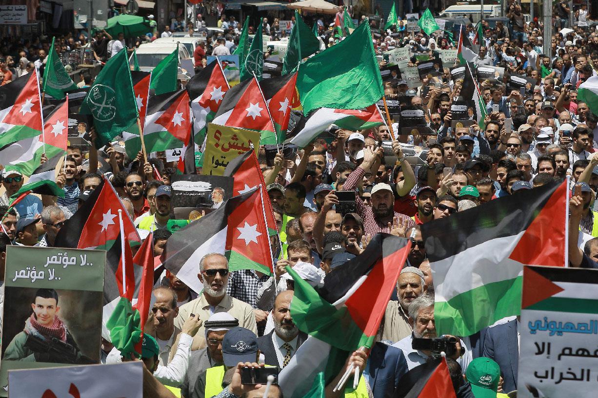 Flags of Jordan and the Muslim Brotherhood are waved with other protest signs denouncing the US-led Middle East economic conference in Bahrain