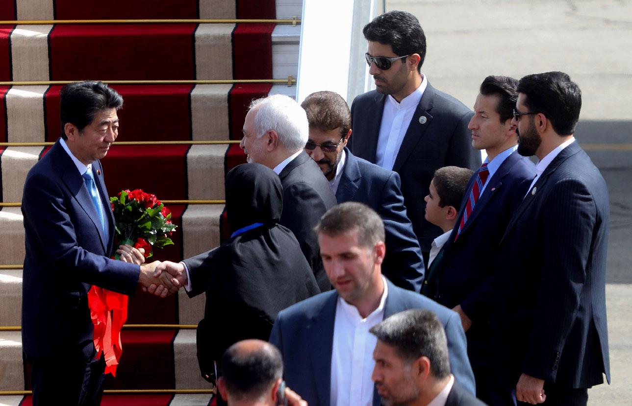 Japan's Prime Minister Shinzo Abe (L) is greeted by Iran's Foreign Minister Mohammad Javad Zarif at Tehran's Mehrabad airport