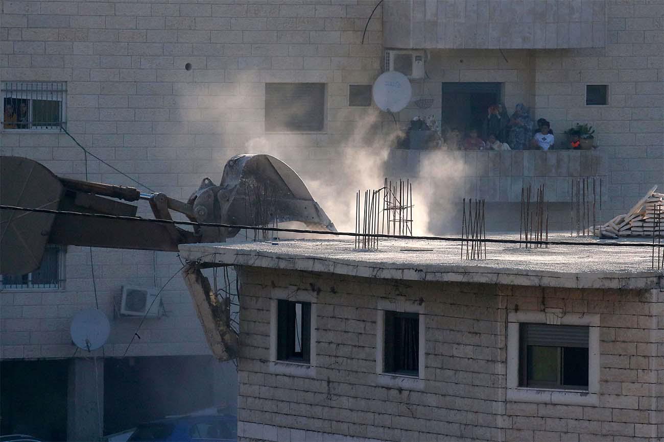 Palestinian family watching Israeli security forces tearing down one of the Palestinian buildings 