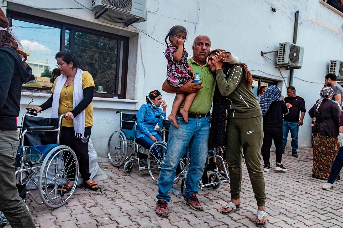 People react as the body of a man killed during Turkish shelling in the area surrounding the Syrian Kurdish town of Ras al-Ain arrives at a hospital in the nearby town of Tal Tamr
