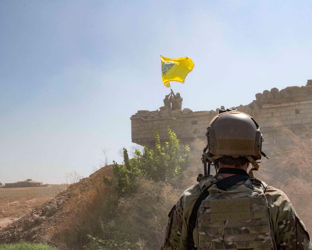 US Soldier oversees members of the Syrian Democratic Forces as they demolish a Kurdish fighters' fortification near Syria's border with Turkey