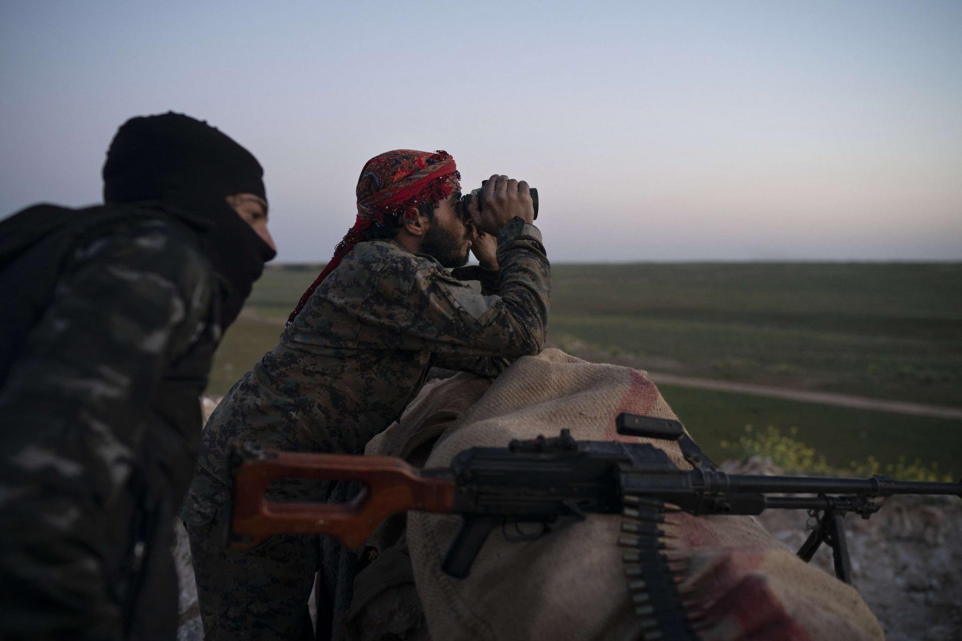 US backed Syrian Democratic Forces fighters survey a position in Baghouz, Syria