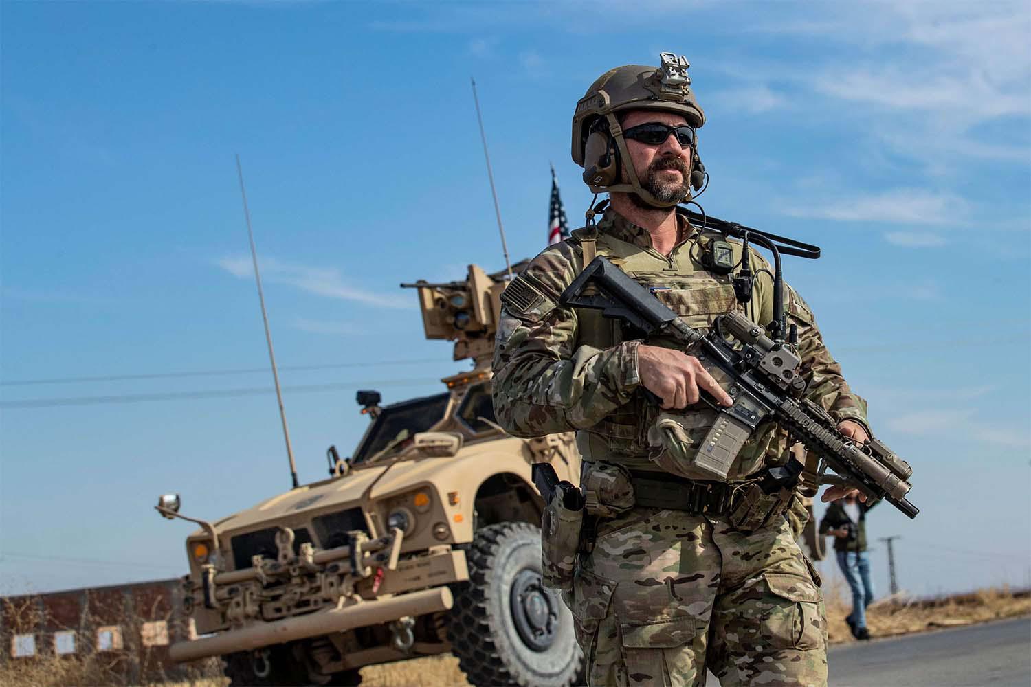 A US soldier stands by an armoured vehicle during a patrol of the northern countryside of the northeastern Syrian town of al-Malikiyah 