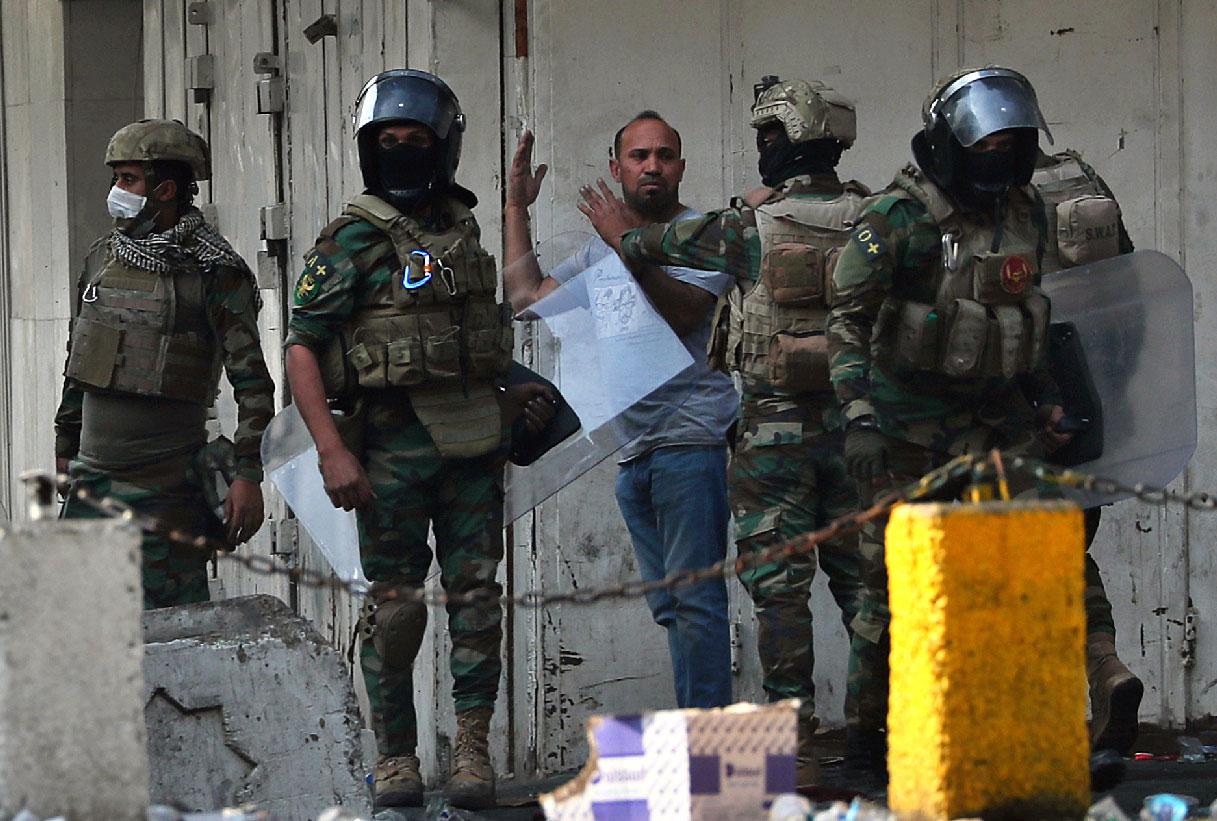 Iraqi security forces arrest a protester in downtown Baghdad