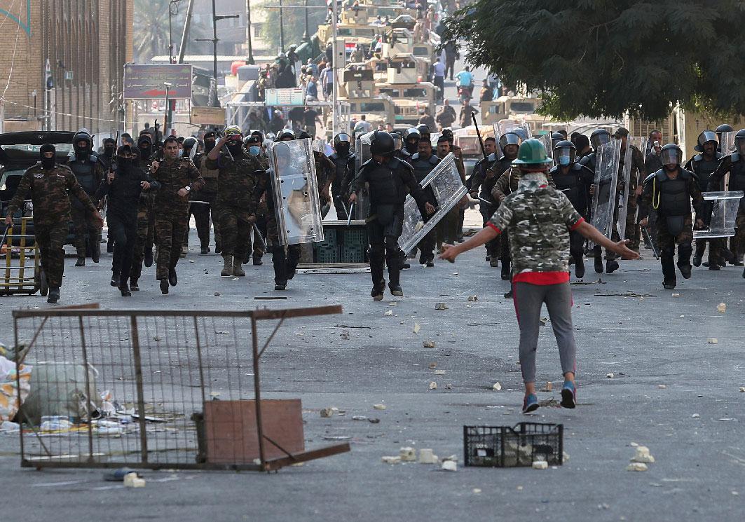Iraqi anti-riot police try to prevent anti-government protesters from crossing the al- Shuhada (Martyrs) bridge