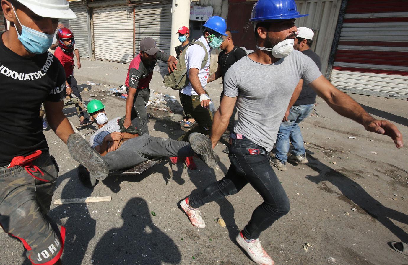 Iraqi demonstrators evacuate a wounded man on the Martyrs' Bridge in Baghdad
