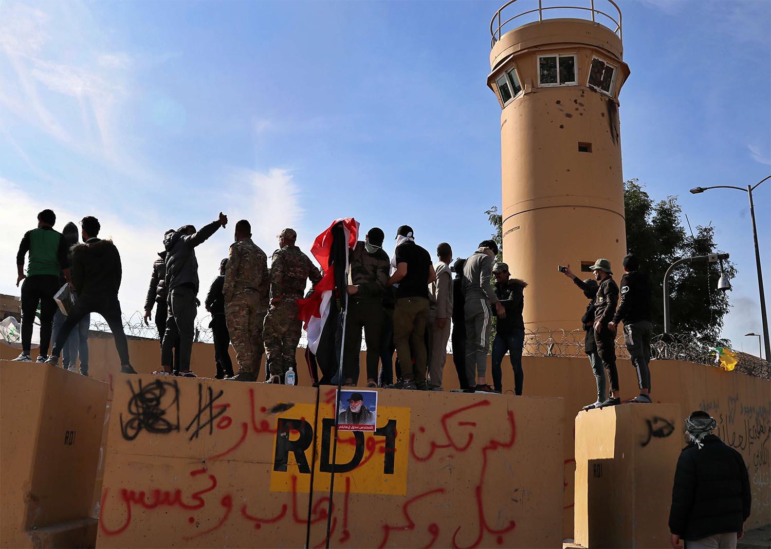 Pro-Iranian militiamen and their supporters look into the US embassy compound in Baghdad