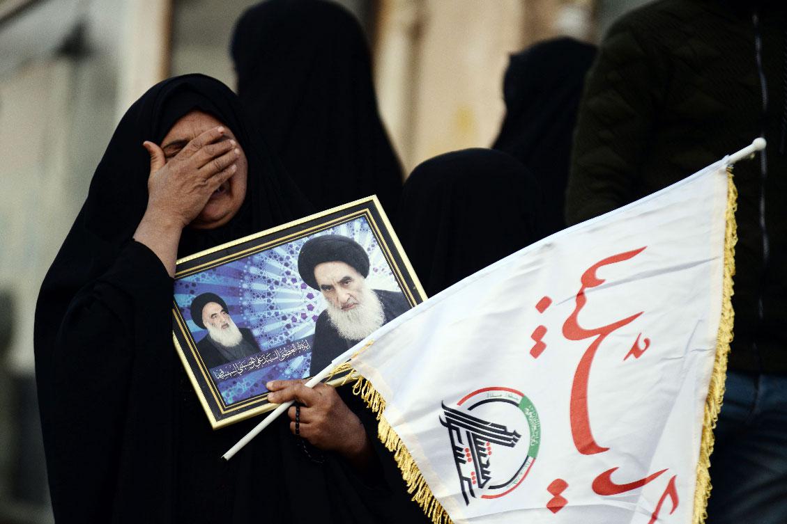 A mourner for Soleimani and Muhandis carries a framed image of Iraq's Grand Ayatollah Ali Sistani