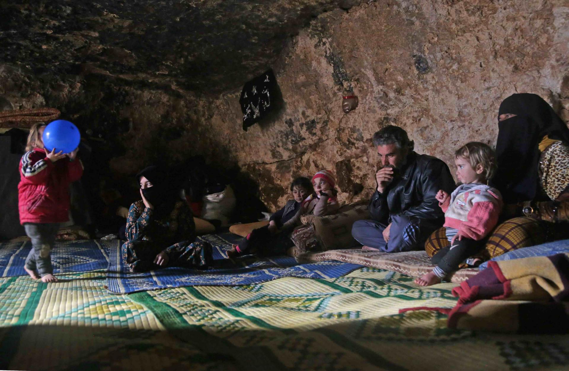 Darra's children huddle on a carpet around a tray covered in small bowls of hummus and dried oregano
