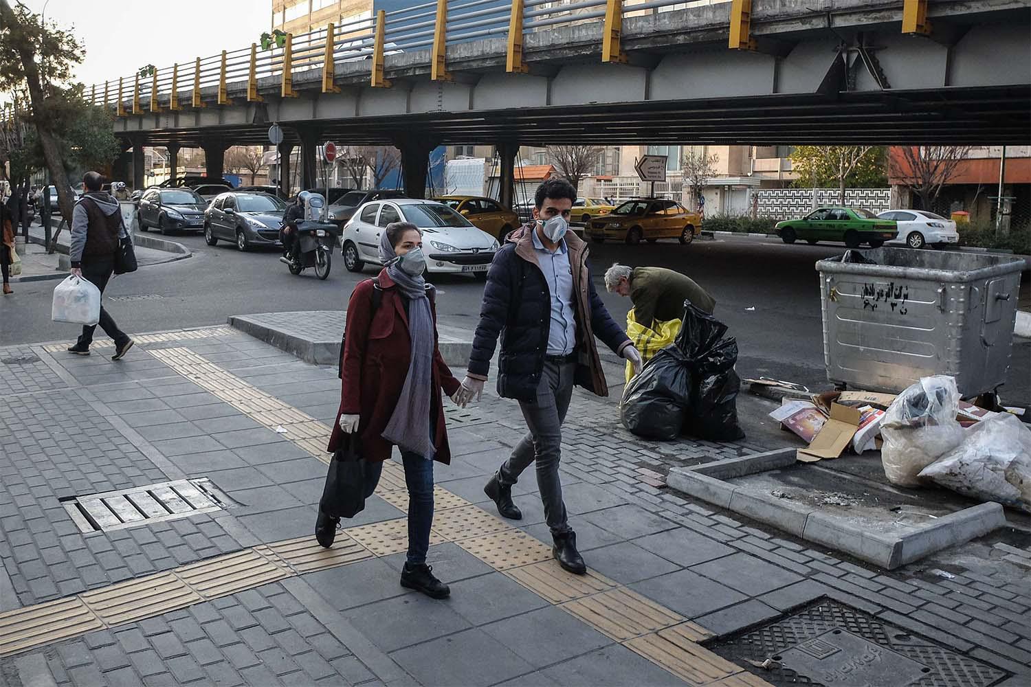Iranians woman wear face protective masks as they walk on a street in the Tehran business district