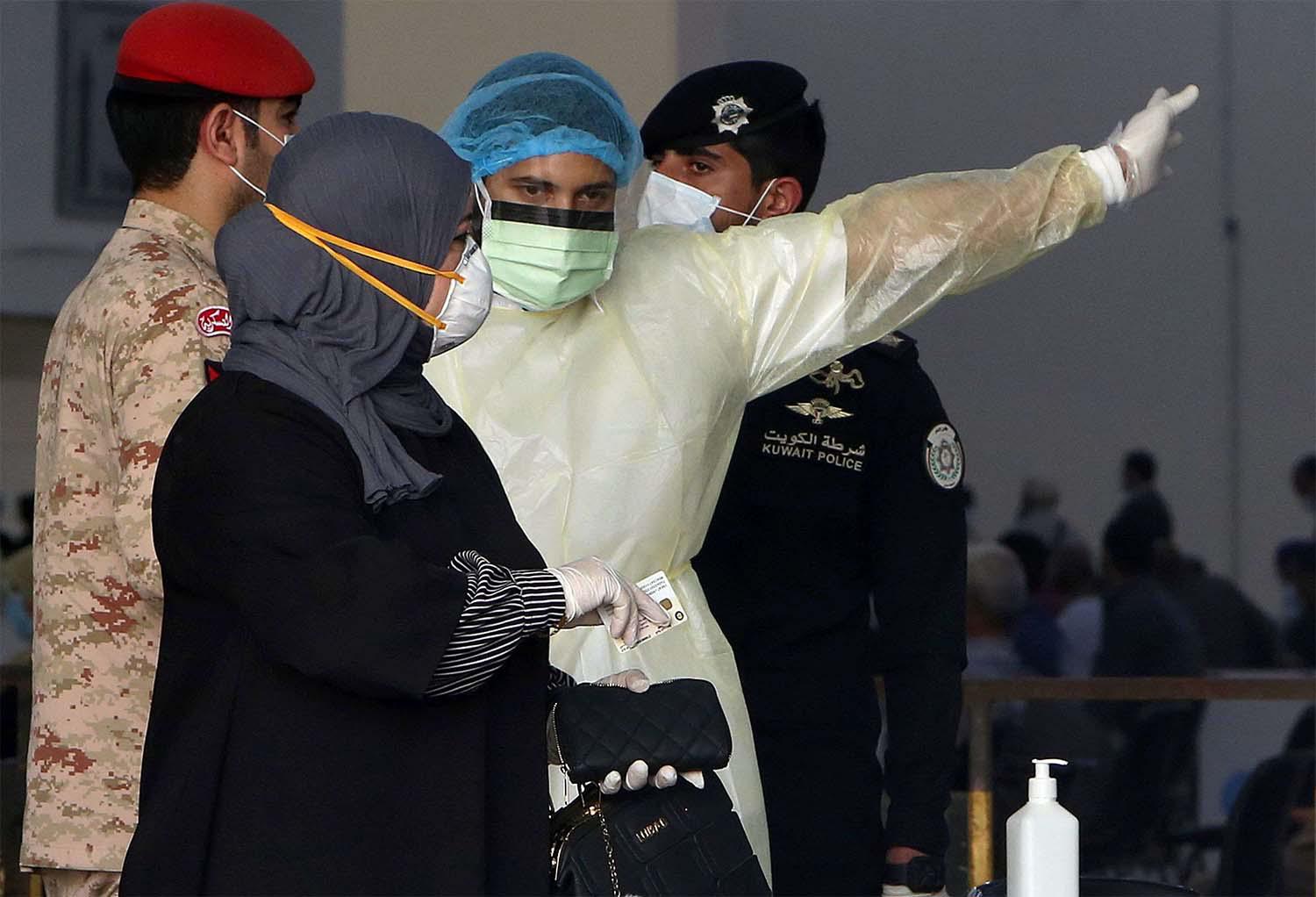 Kuwaiti healthy ministry workers prepare to scan expatriates living in Kuwait who returned from Egypt, Syria and Lebanon