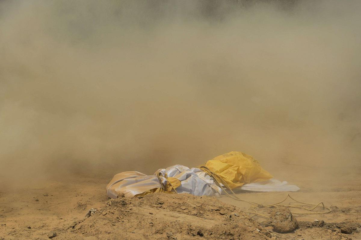 الغبار يغطي جثة امرأة توفيت بكورونا قبل دفنها في مقبرة في نيودلهي
