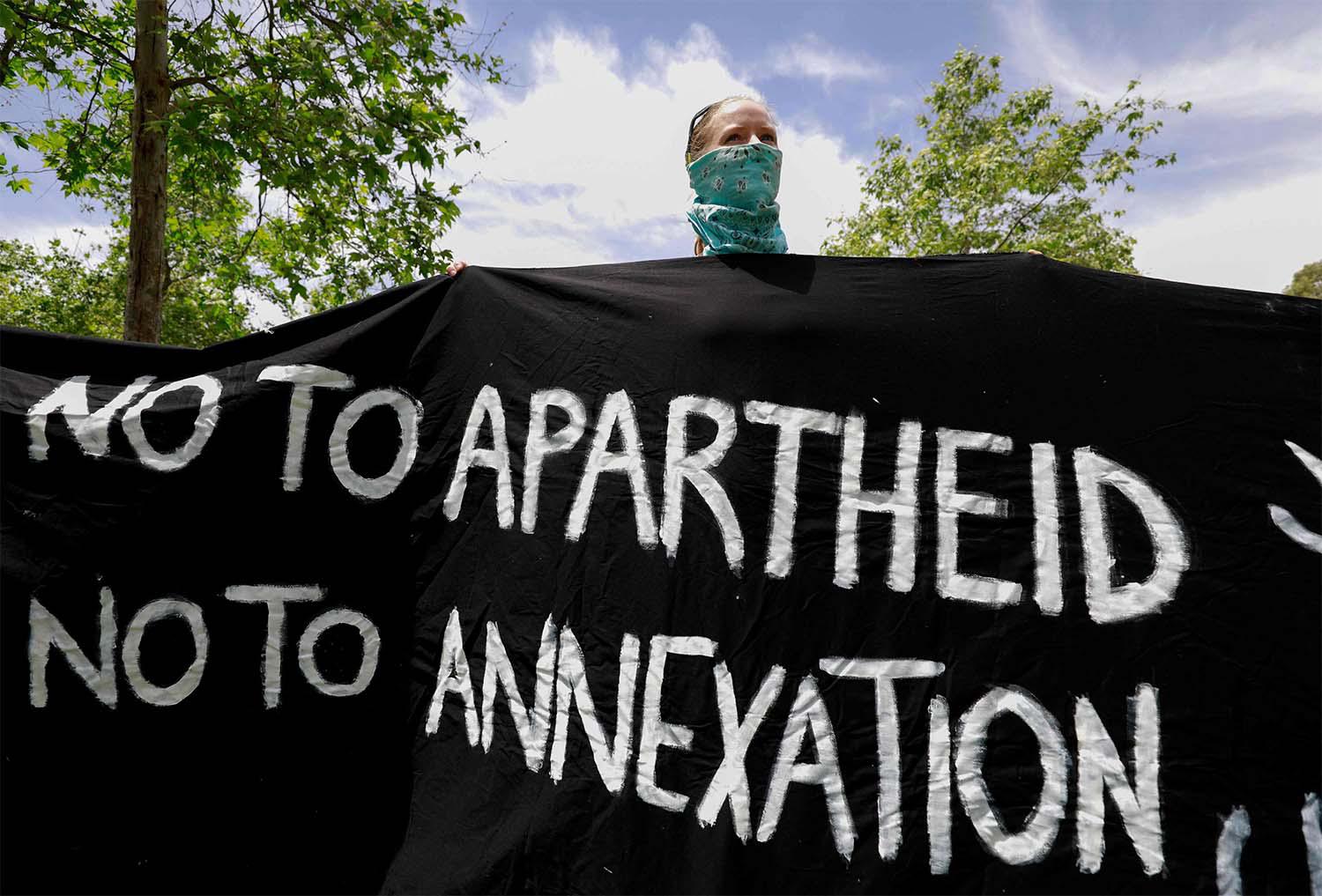 Israeli activist holds a banner during a protest against the US peace plan for the Middle East, in front of the US ambassador's residence in Jerusalem
