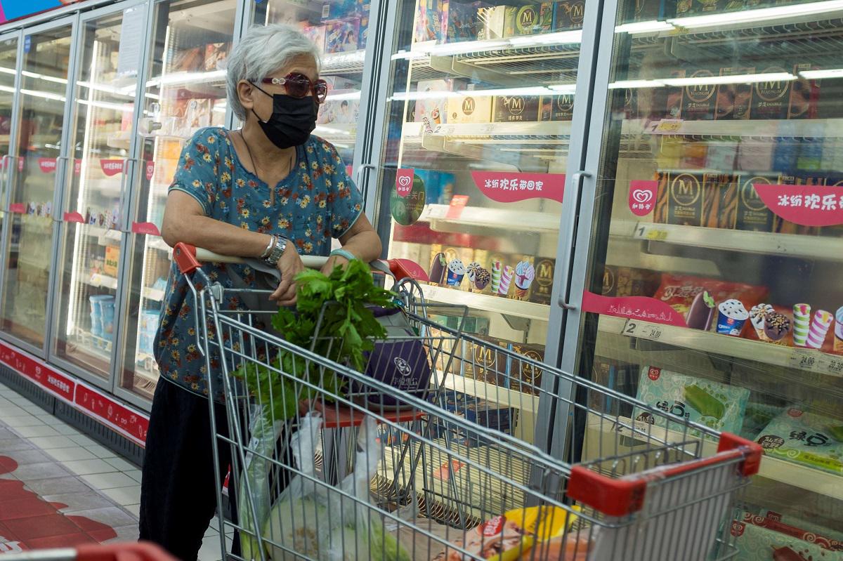 متسوقة صينية أمام ثلاجات الأغذية المجمدة
