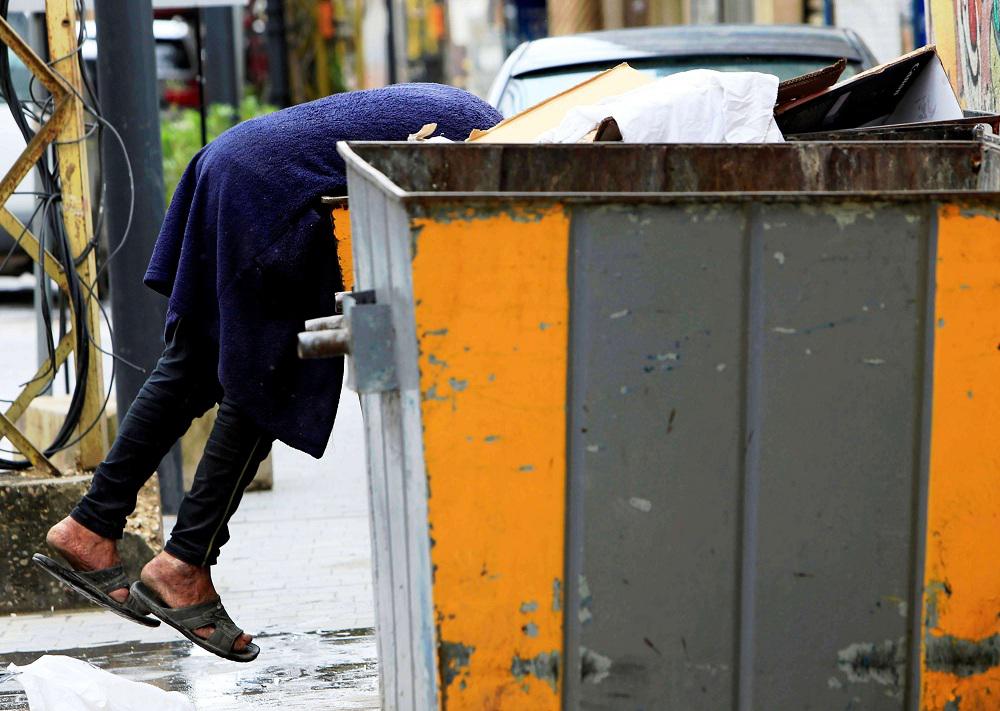 في مشهد يختزل مأساة اللبنانيين.. رجال ونساء يبحثون عن الطعام في حاويات القمامة 