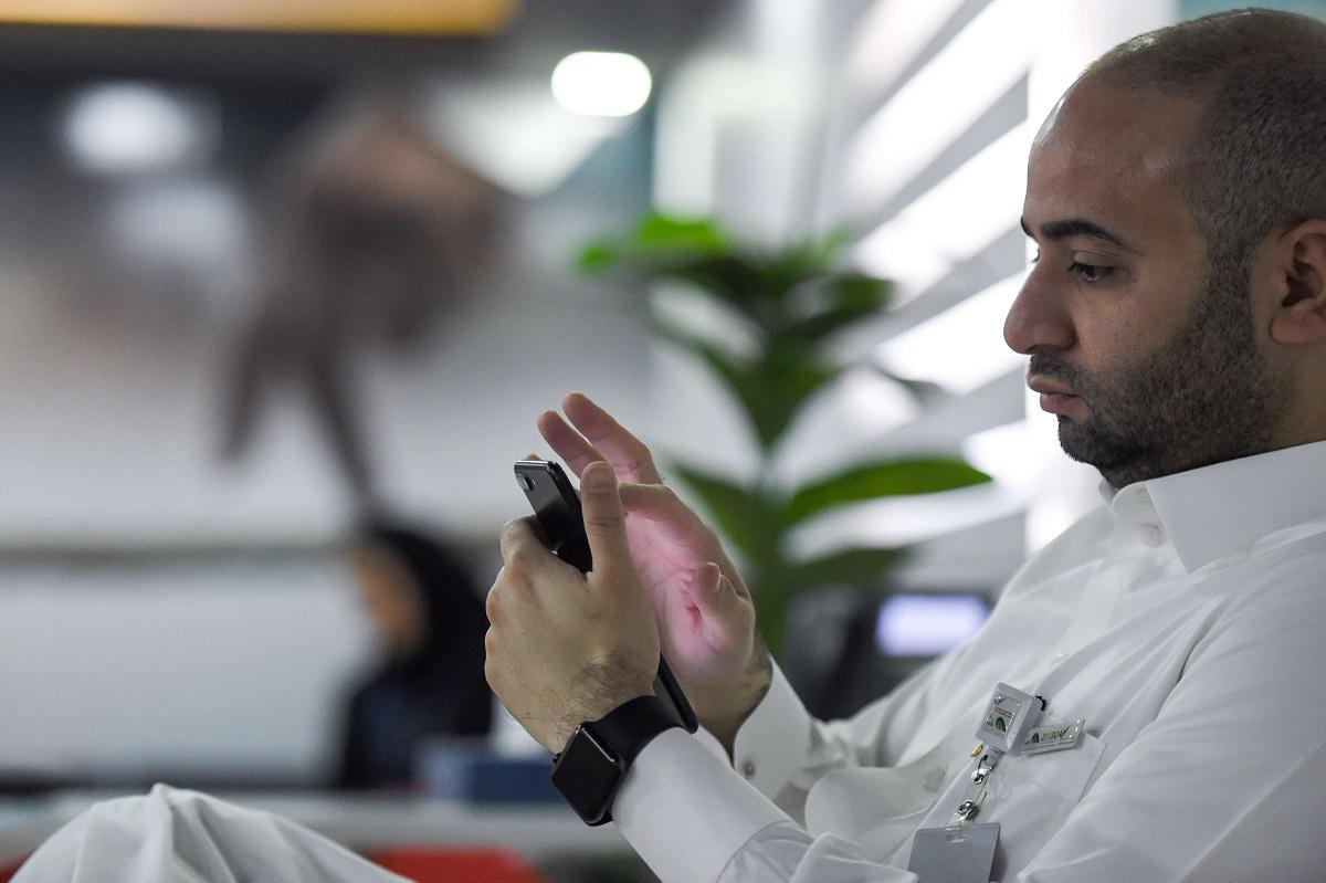 موظف سعودي يتفقد هاتفه المحمول في مكتبه بالعاصمة الرياض