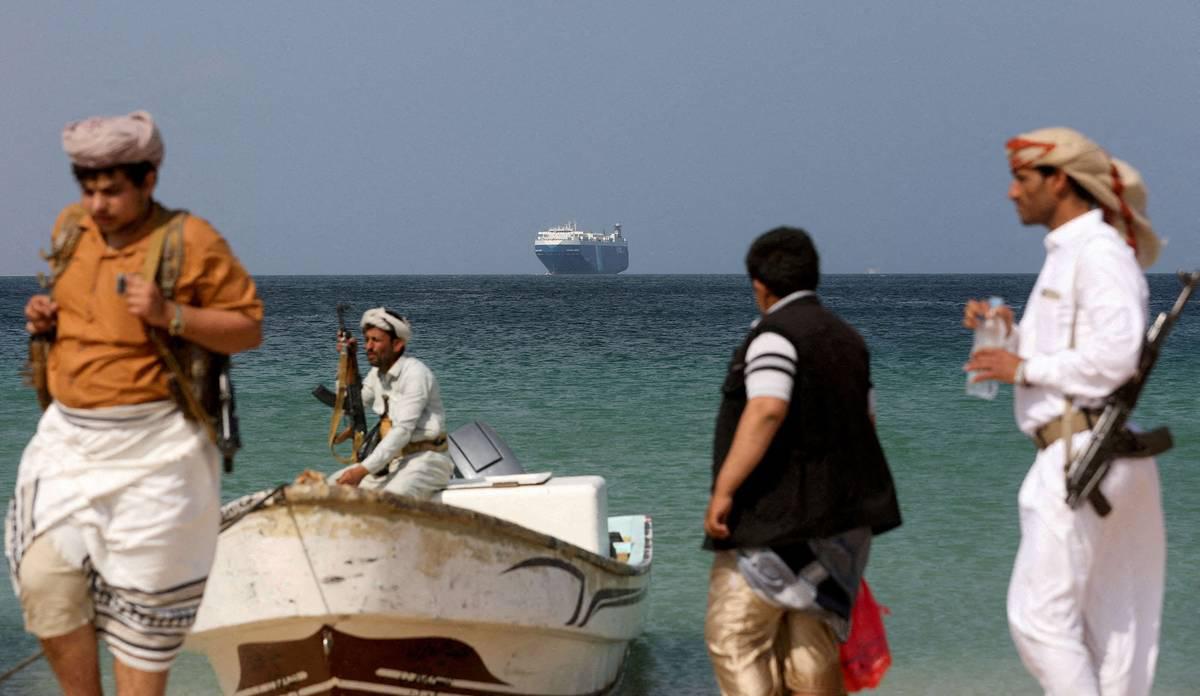 مسلحون حوثيون ينظرون إلى سفينة شحن تم ايقافها في البحر الأحمر