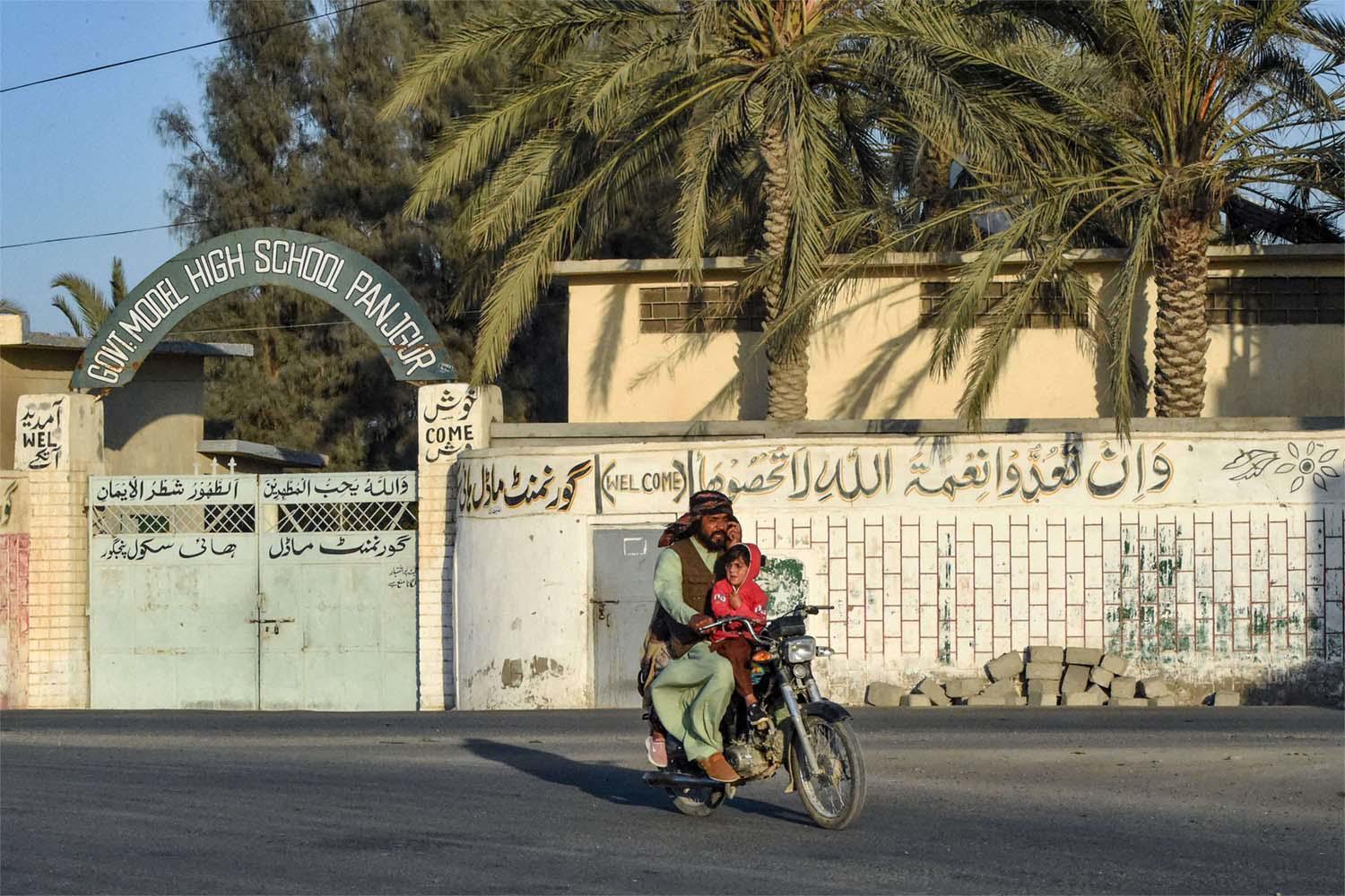 A motorcyclist rides past a high school at Panjgur district in Balochistan province 